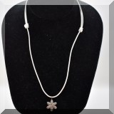 J135. White leather cord with pave diamond flower pendant.  